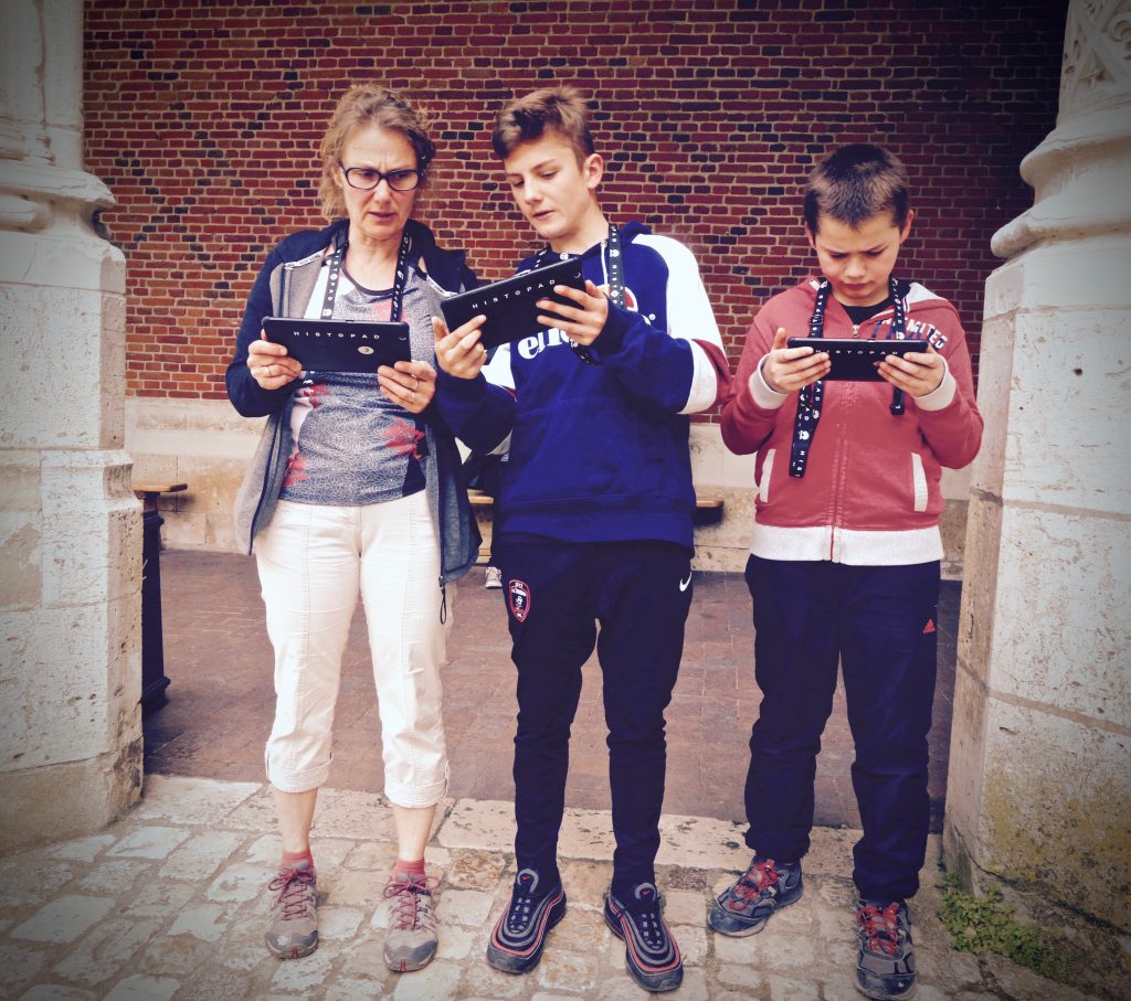three people reading their phablet during a tour in a chateau