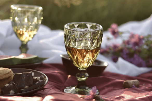 two yellow glasses on a picnic blanket during a gourmet tour