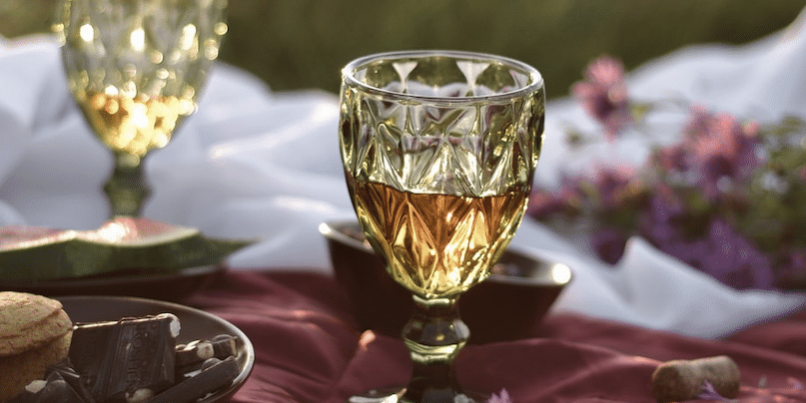 two yellow glasses on a picnic blanket during a gourmet tour