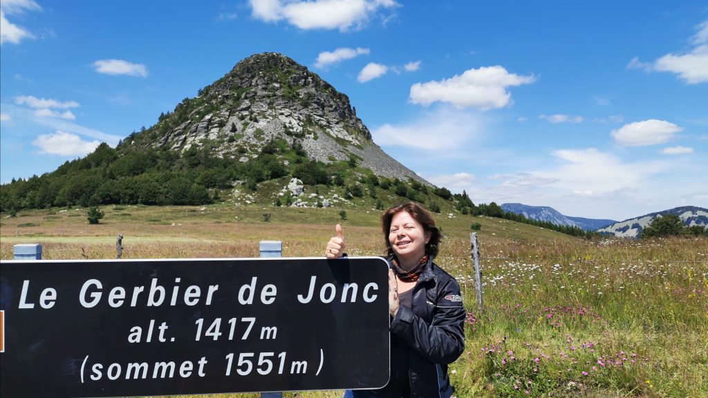 a woman standing next to a sign in the mountain