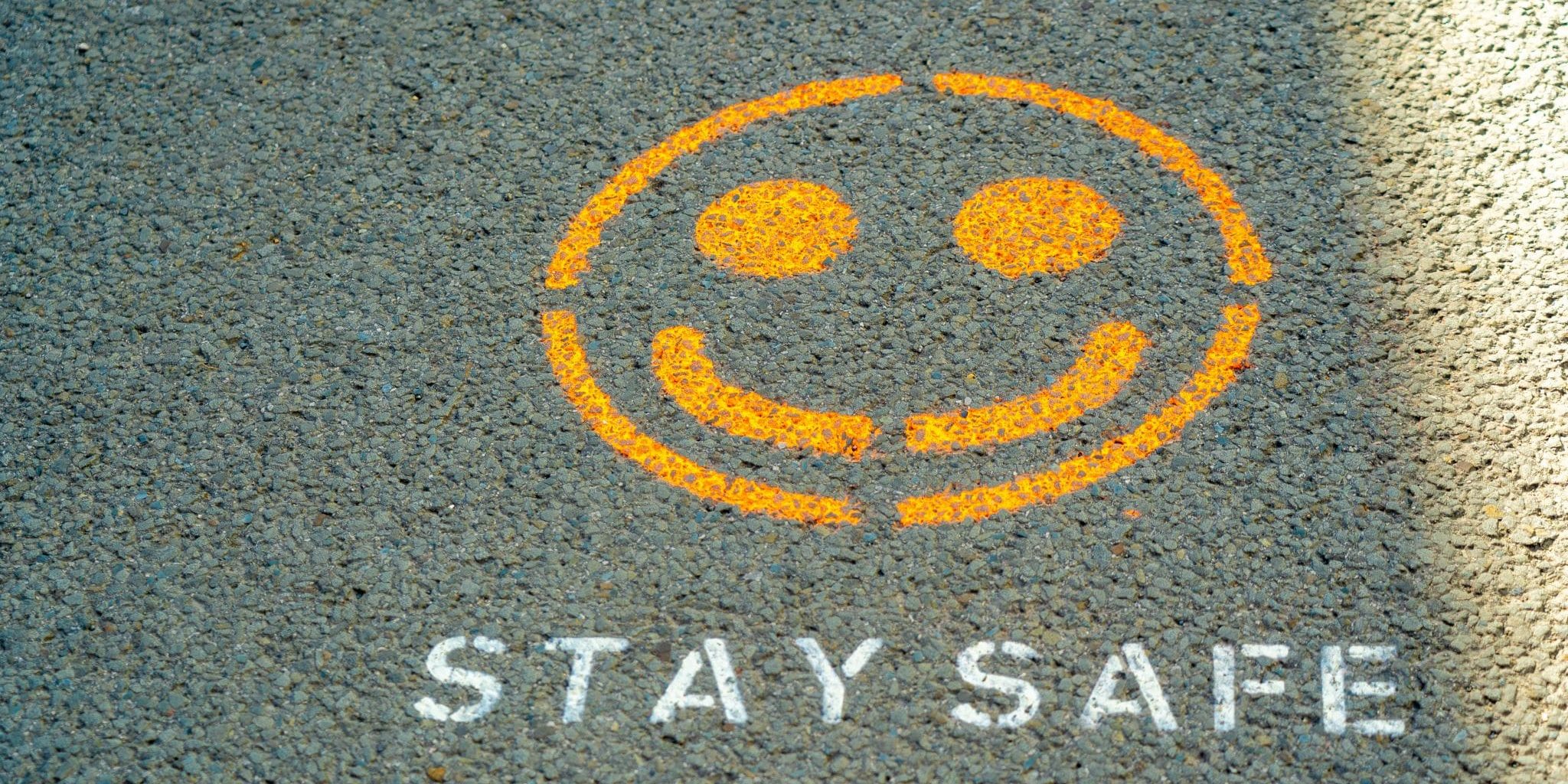a stay safe sign and a smiley on the ground