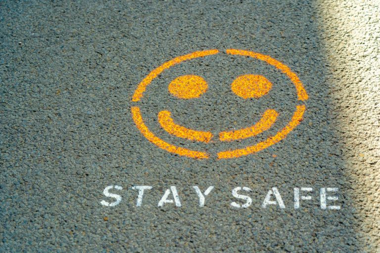 a stay safe sign and a smiley on the ground