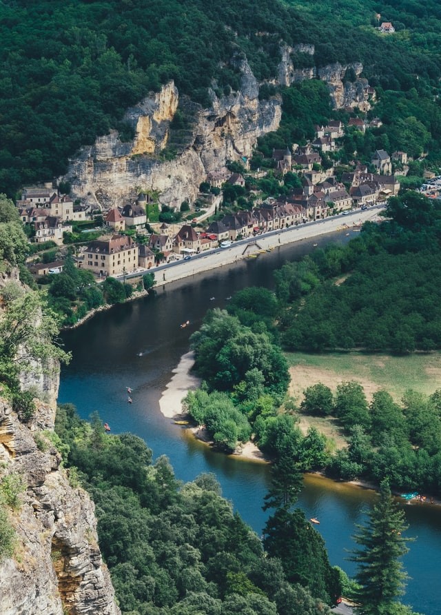 an aerial view of a medieval village along a river in dordogne