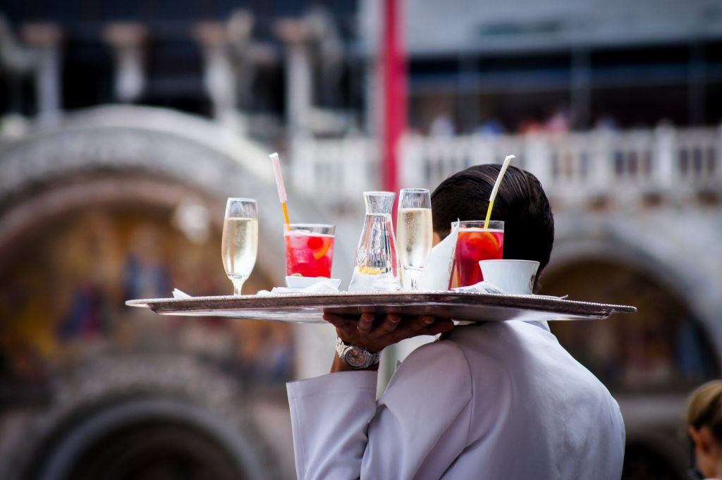 a waiter in france holding a plate of drinks