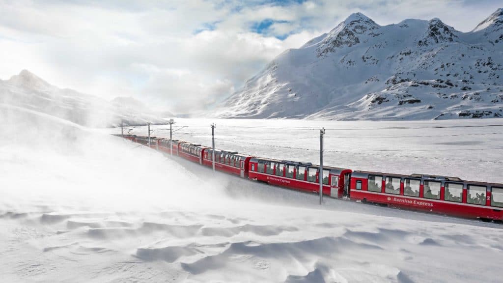 a red train through a snow scenery in the alps