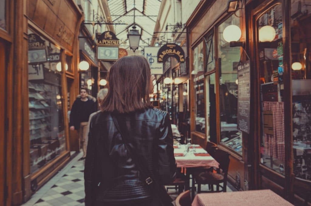 a woman walking between small cafes in france