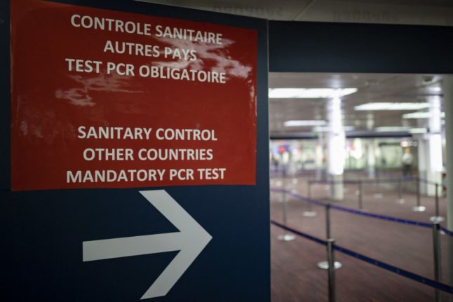 A sign indicates the way to a sanitary control point for passengers arriving at paris airport